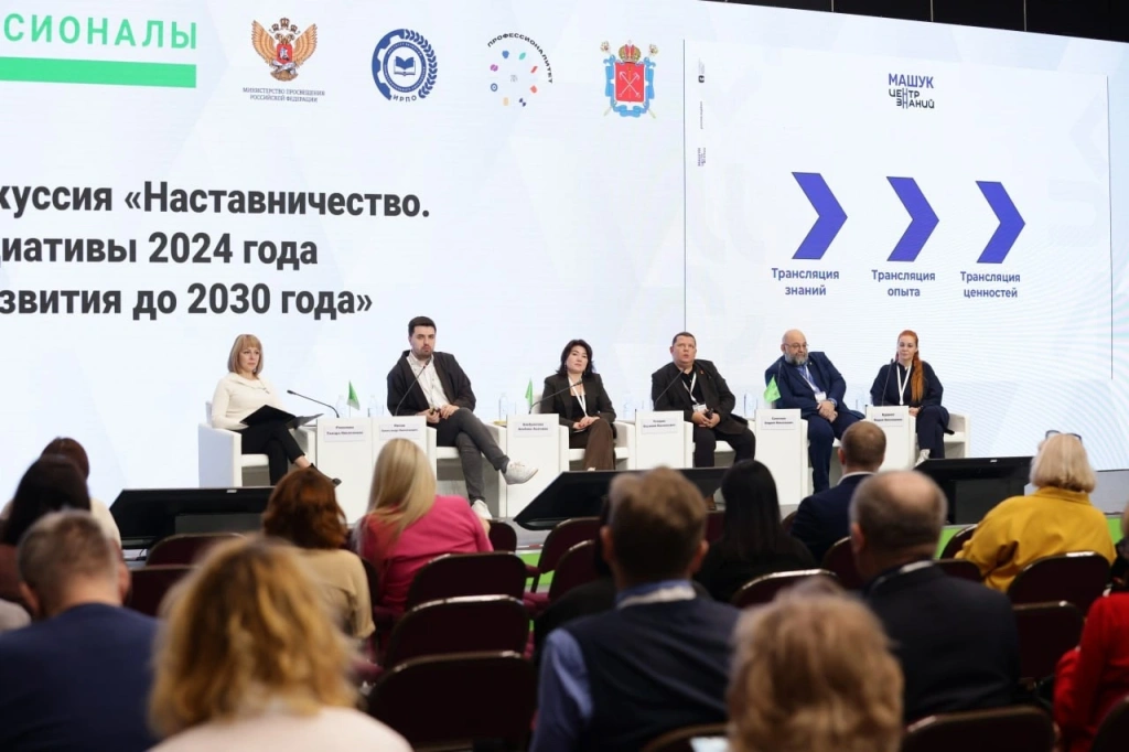 На изображении показана панельная дискуссия, на которой присутствуют шесть человек, сидящих на сцене в креслах. На заднем плане виден большой экран с текстом и логотипами. На экране написано: "Дискуссия «Наставничество. Инициативы 2024 года и развития до 2030 года». Также на экране есть логотипы Министерства просвещения Российской Федерации и других организаций. Справа на экране изображены три стрелки с подписями: "Трансляция знаний", "Трансляция опыта", "Трансляция ценностей". В зале сидят зрители, которые слушают выступающих.
Среди спикеров события-Андрей Самотоин, исполнительный директор ВОД "Наставники России". Он рассказал об инициативе расширения категории граждан для награды «За наставничество» и значении профессионального обучения для молодежи.

